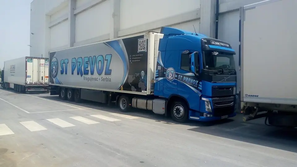 Plavi Volvo sa poluprikolicom ST PREVOZ na rampi skladišta